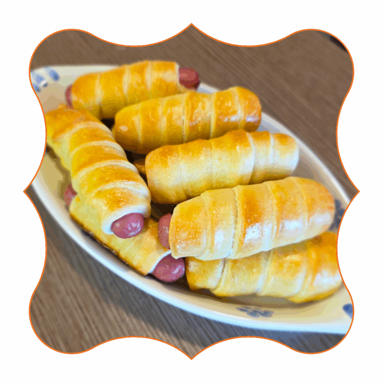 Mini hot dog avvolti in pasta sfoglia dorata su piatto ovale, antipasto facile per feste