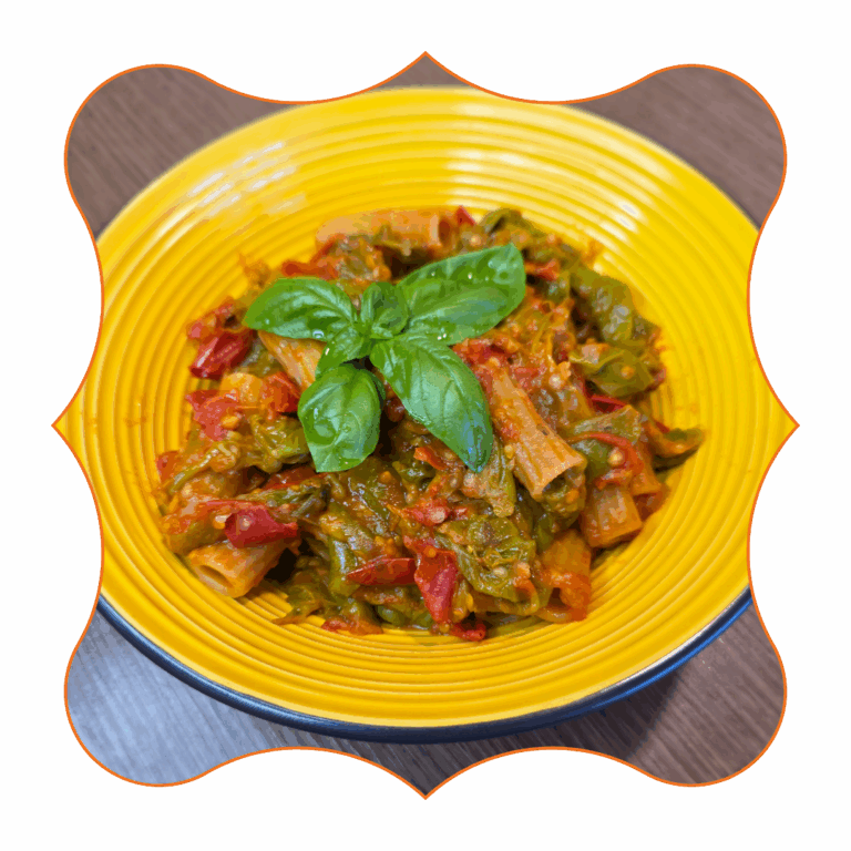Rigatoni con sugo di peperoni verdi e pomodorini, guarniti con foglia di basilico in ciotola gialla