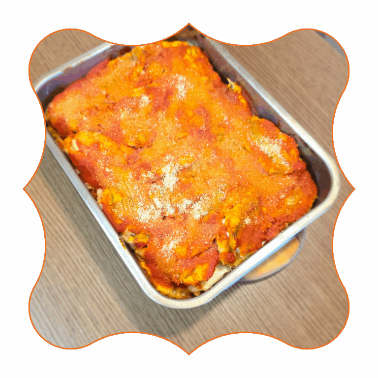 Teglia di parmigiana di alici al forno con pomodoro e pangrattato su tavolo in legno