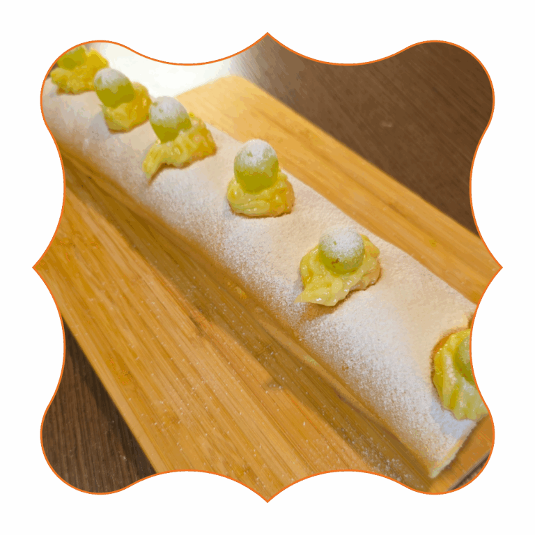 Dolce Bacco, rotolo di pasta soffice farcito e decorato con crema pasticcera e chicchi d’uva, spolverato con zucchero a velo.